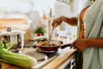 In a close up shot of a cooktop, a woman is seen preparing a dish filled with healthy ingredients.