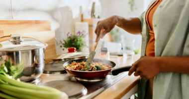 In a close up shot of a cooktop, a woman is seen preparing a dish filled with healthy ingredients.