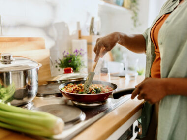 In a close up shot of a cooktop, a woman is seen preparing a dish filled with healthy ingredients.