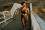 An image of a woman in athletic clothing running up outdoor stairs.