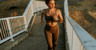 An image of a woman in athletic clothing running up outdoor stairs.