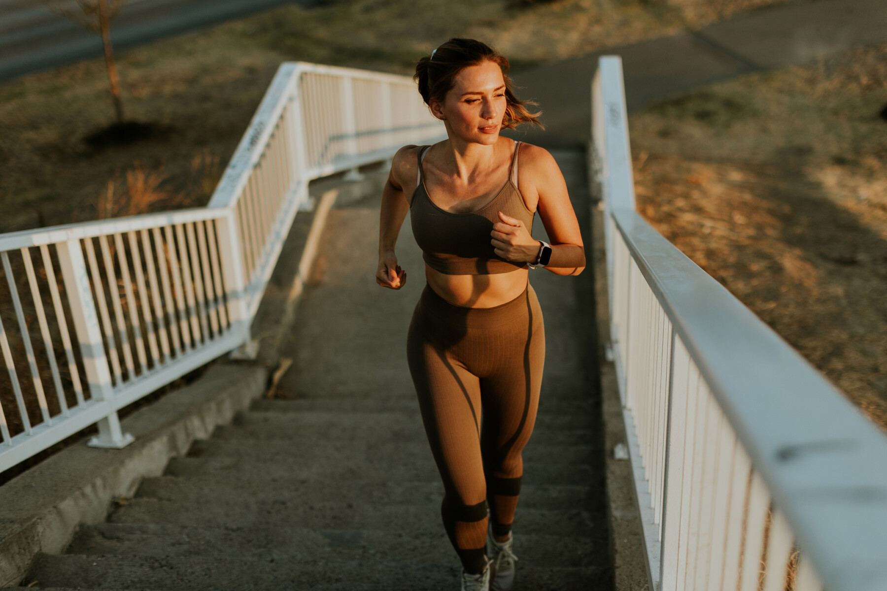 An image of a woman in athletic clothing running up outdoor stairs.