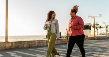 Two people walk on a boardwalk.