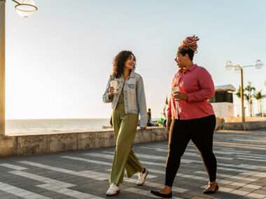 Two people walk on a boardwalk.