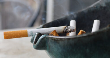 A closeup of a burning cigarette in an ashtray.