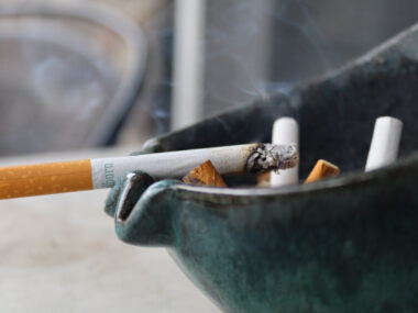 A closeup of a burning cigarette in an ashtray.