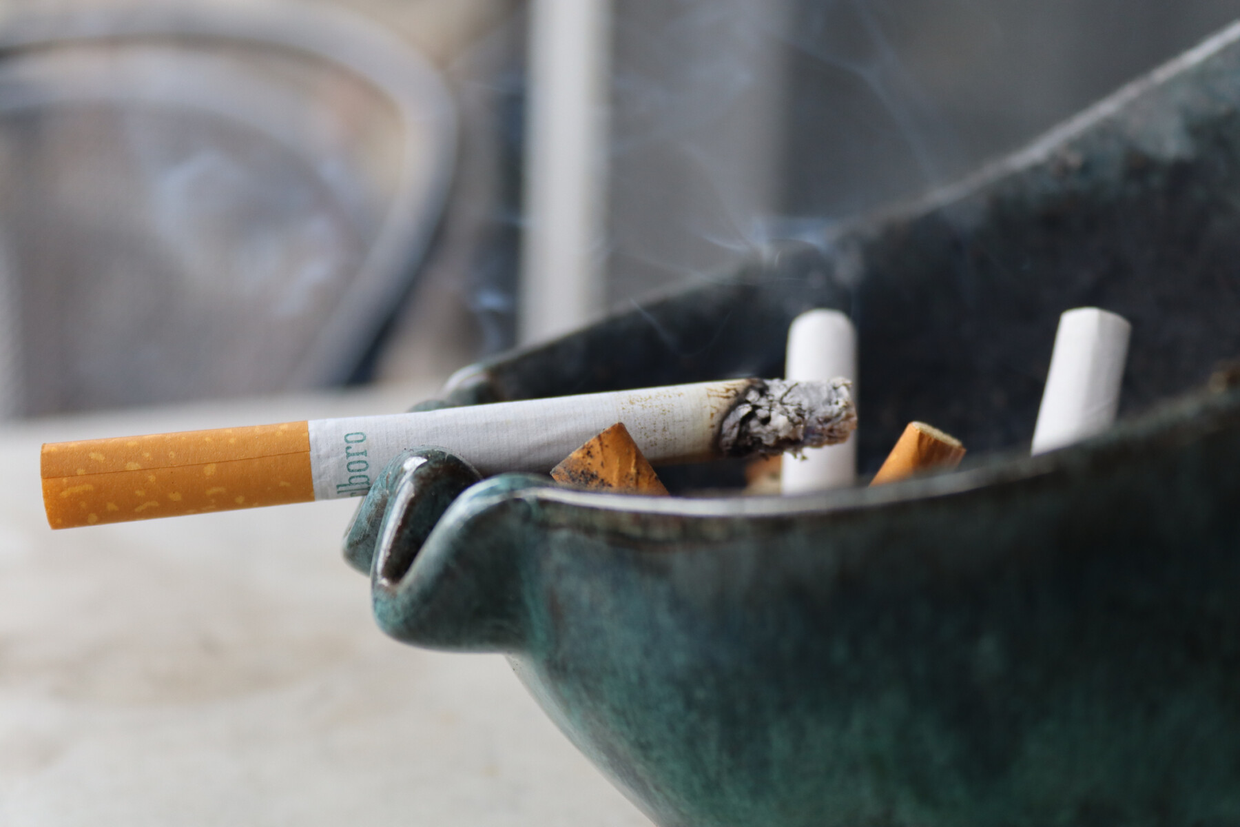 A closeup of a burning cigarette in an ashtray.