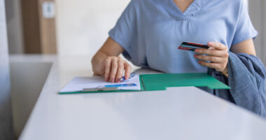A nurse holds a card while filling out a form.