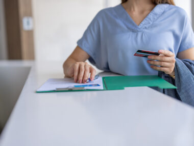 A nurse holds a card while filling out a form.