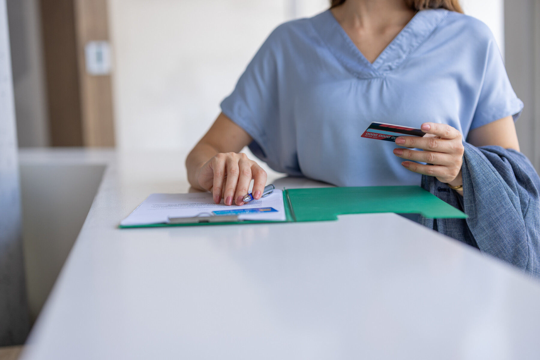 A nurse holds a card while filling out a form.