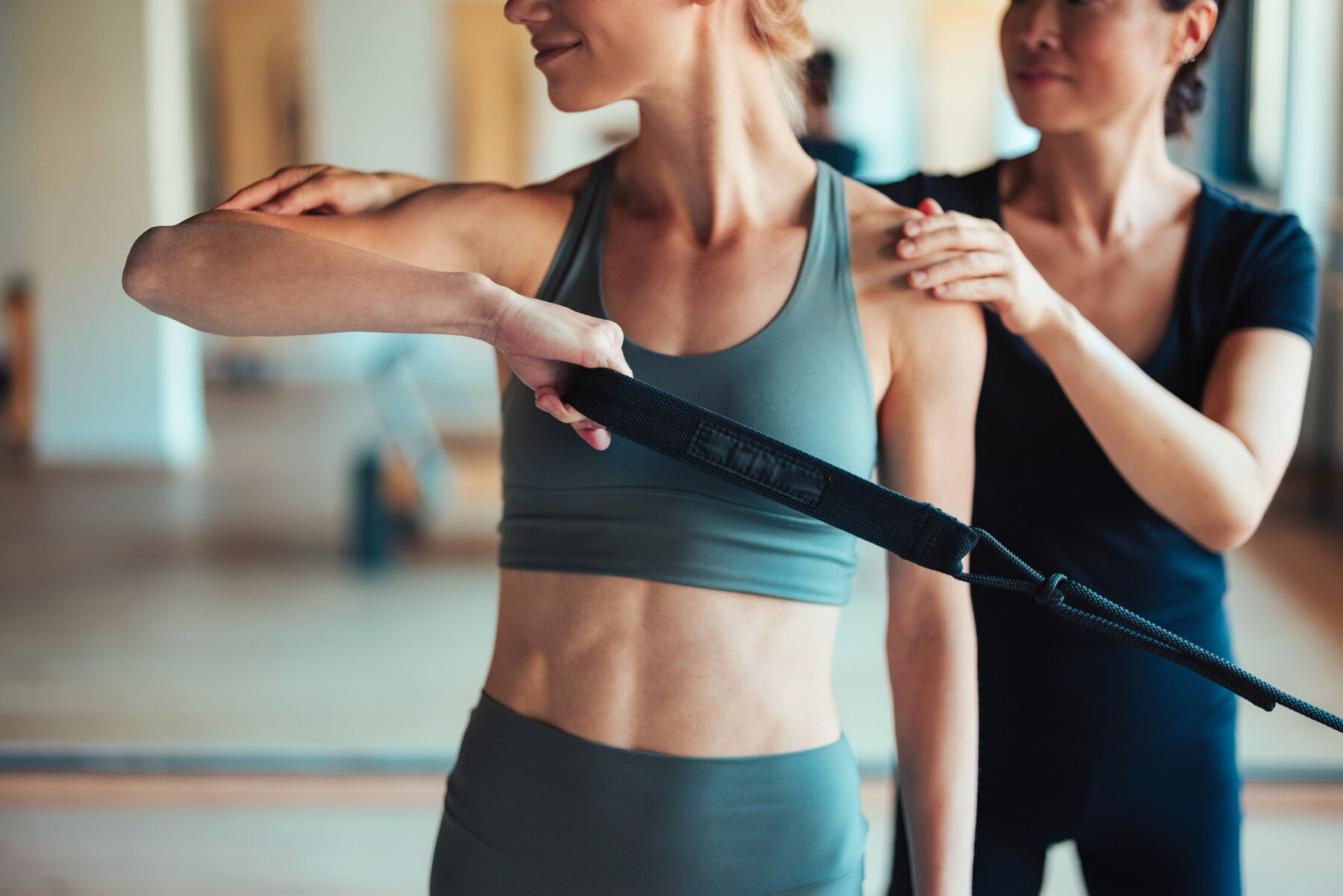 A fitness instructor provides individualized guidance to a woman performing strength exercises with a resistance band.