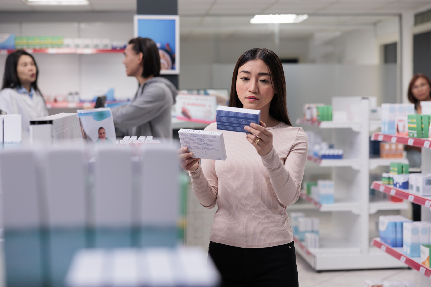A person examines a box of medication in a drugstore.