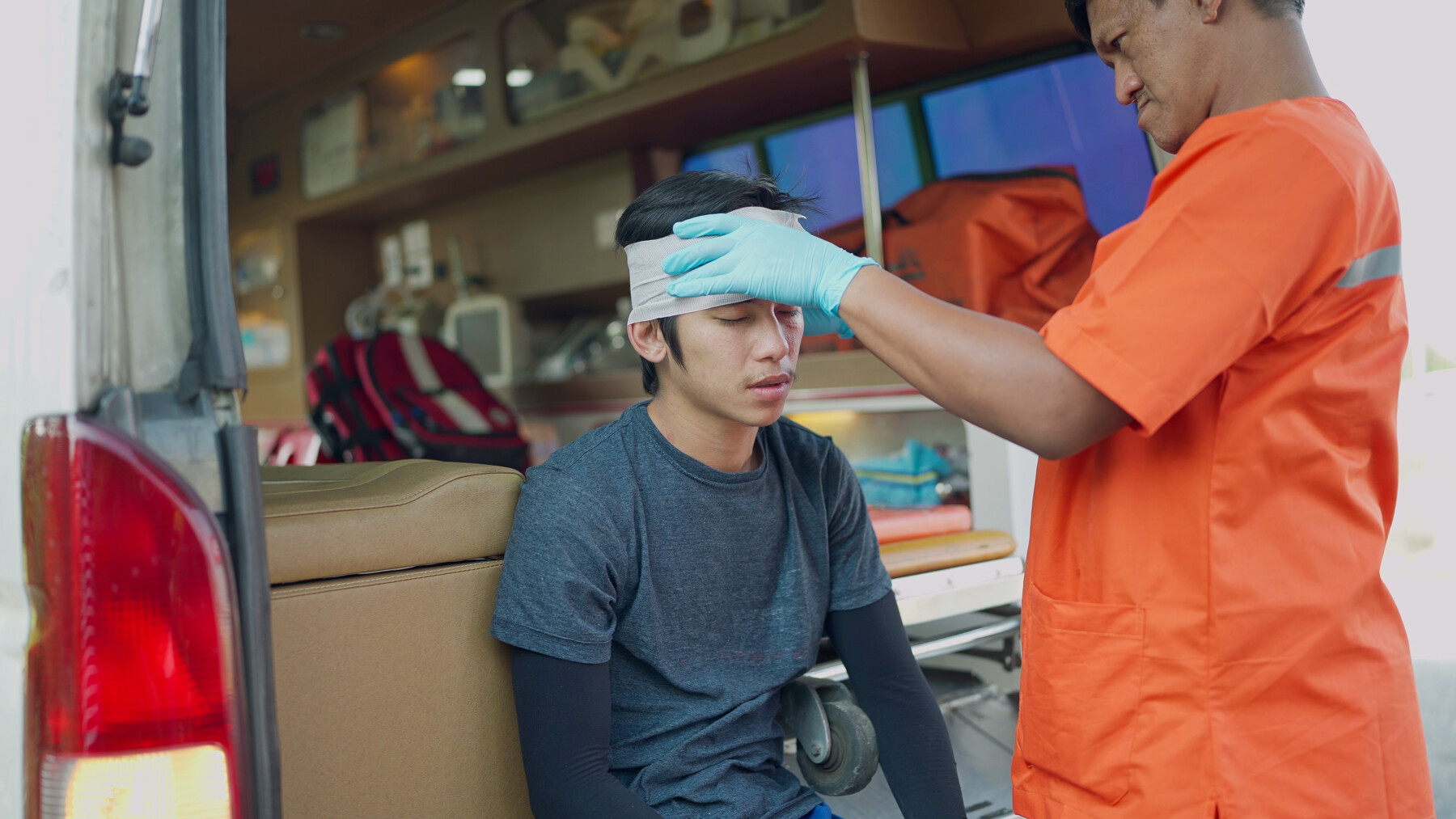 A medical professional wraps a bandage around the head of a young person who sustained an apparent head injury.