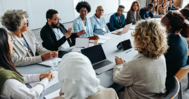 A group of people sit around a conference table.