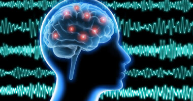Against a backdrop of brain waves, the profile of a human head shows electrical activity in the brain.