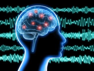 Against a backdrop of brain waves, the profile of a human head shows electrical activity in the brain.