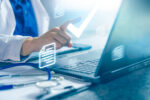 A doctor is seen inputting medical data on a laptop.