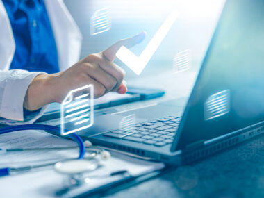 A doctor is seen inputting medical data on a laptop.