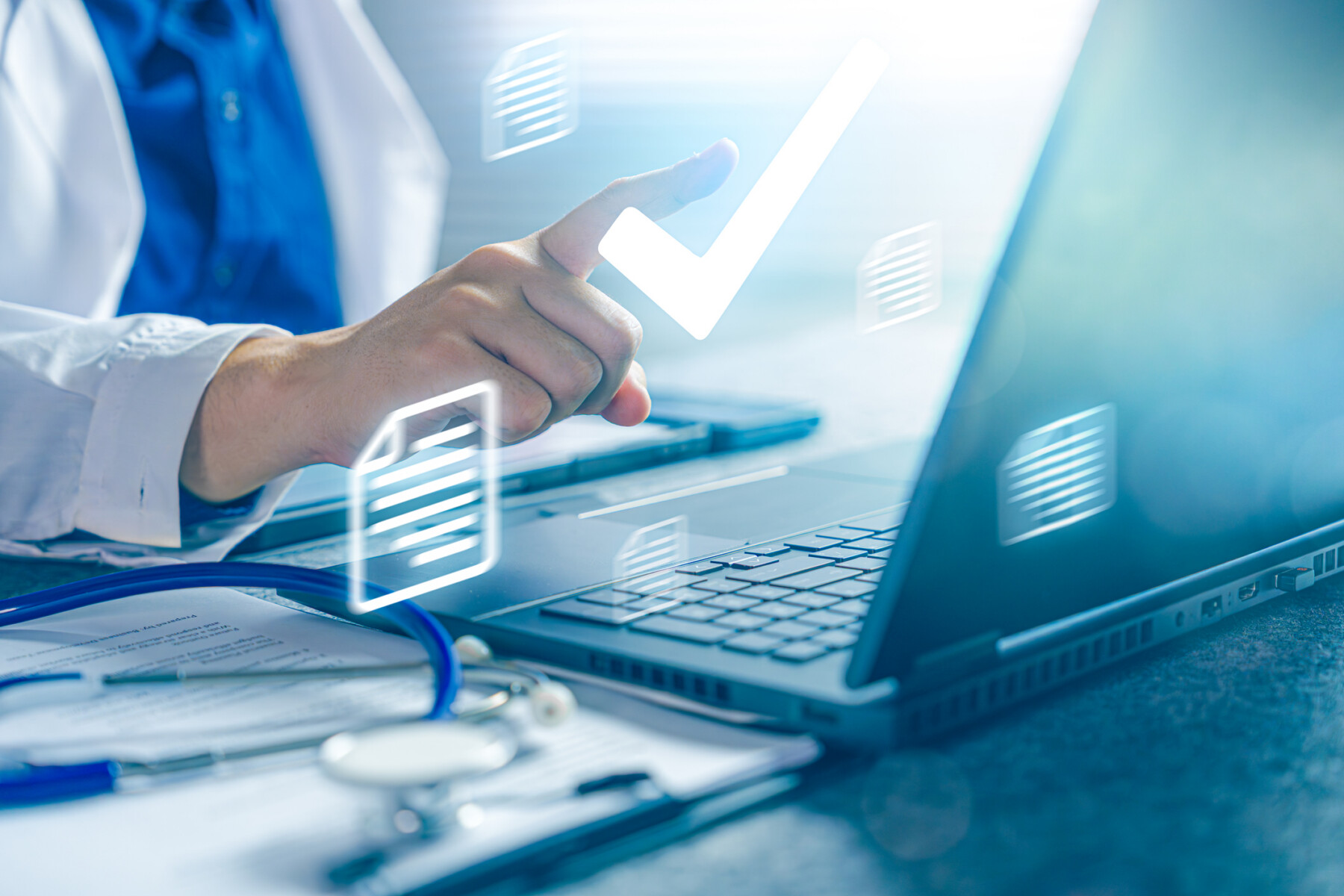 A doctor is seen inputting medical data on a laptop.