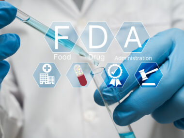 Icons reading F, D, A, and showing clinical trial elements are superimposed on an image of two gloved hands using a dropper to fill a vial.