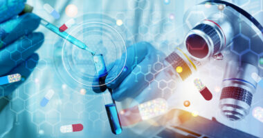 A researcher with blue-goved hands uses a dropper to add a liquid to a vial.