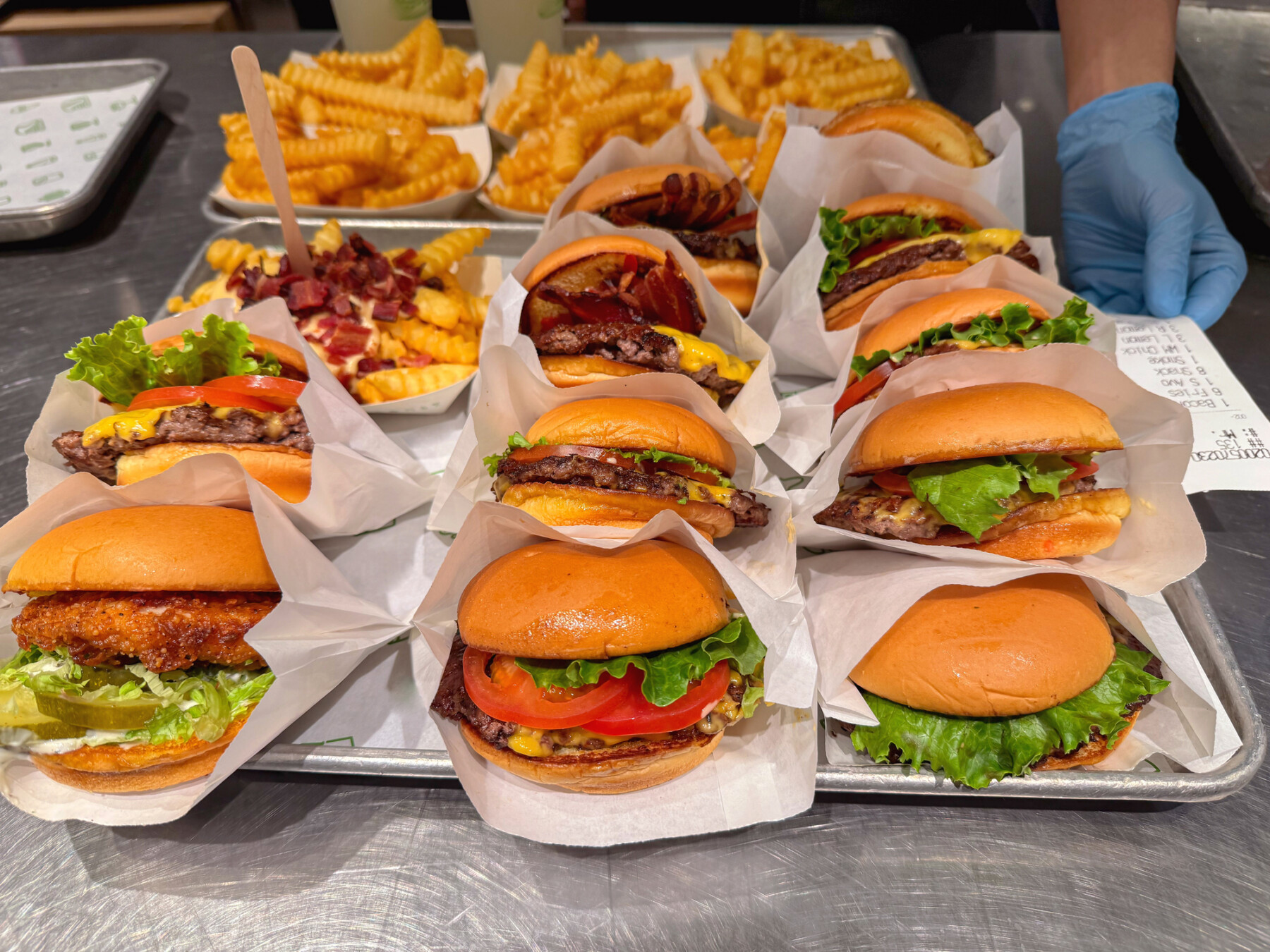 Freshly made cheeseburgers and fries are lined up in individual wrappers in a restaurant kitchen.
