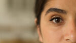 A close-up of a woman's face highlights one of her eyes.