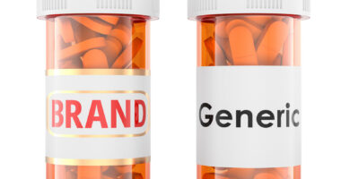 Two prescription bottles labeled “Brand” and “Generic,” each filled with orange capsules.