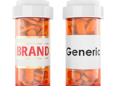 Two prescription bottles labeled “Brand” and “Generic,” each filled with orange capsules.