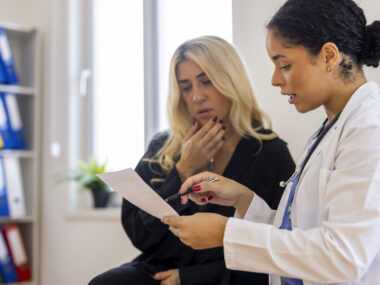 A doctor holds a document while consulting with a patient.