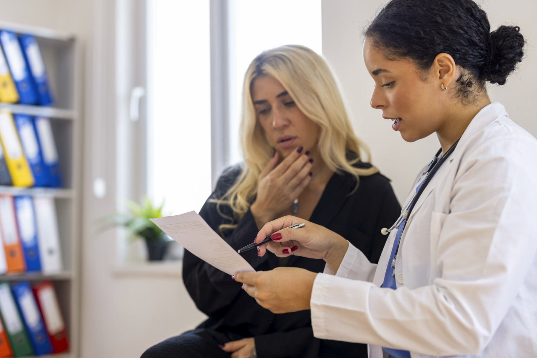 A doctor holds a document while consulting with a patient.